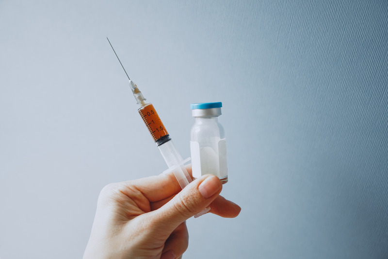 A syringe and vial being held in someone's hand.