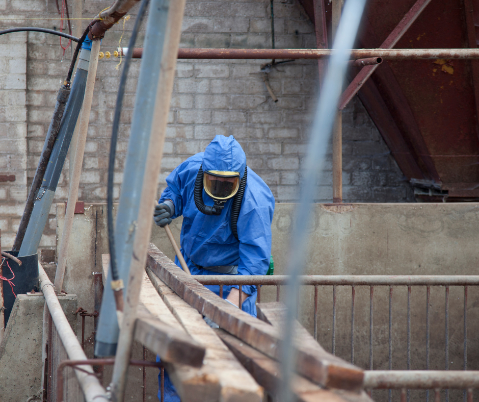 Man in blue protective suit removing asbestos