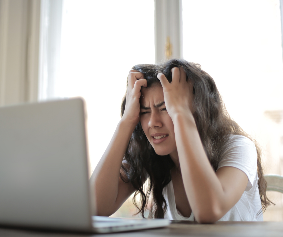 Woman sat at a laptop holding her head in frustration